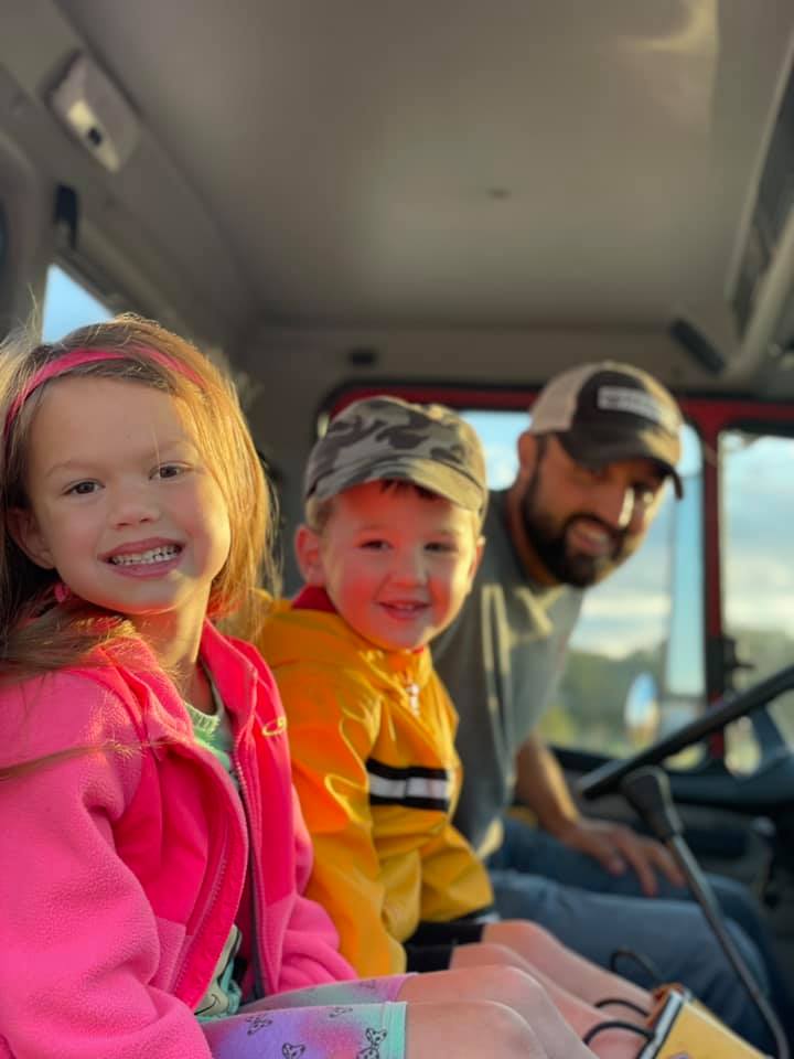 two children sitting in a truck with their father