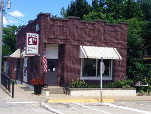 A small, red brick bank building with a sign reading 